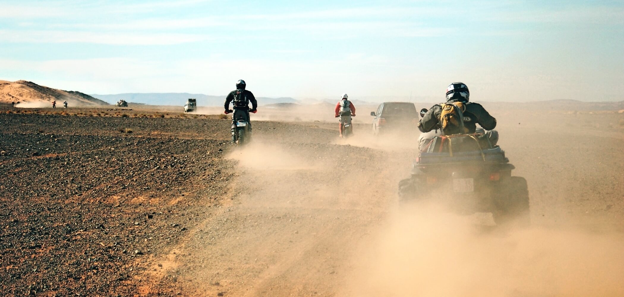 Desert quad biking adventure in Morocco Group riding quad bikes across golden desert dunes under a wide open sky in Morocco.